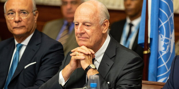 Staffan de Mistura sitzt vor einer UN-Flagge an einem Tisch