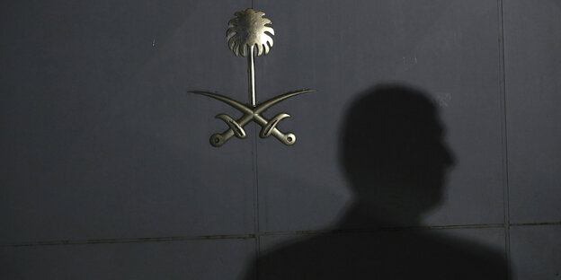 Schatten eines Menschen auf einer Tür mit saudischem Staatswappen Schatten eines Menschen auf einer Tür mit saudischem Staatswappen