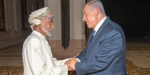 Der omanische Sultan Qaboos und der israelische Ministerpräsident Netanjahu stehen sich gegenüber und schütteln Hände Der omanische Sultan Qaboos und der israelische Ministerpräsident Netanjahu stehen sich gegenüber und schütteln Hände