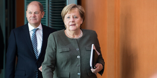 Finanzminister Olaf Scholz läuft hinter Bundeskanzlerin Angela Merkel in einen Raum Finanzminister Olaf Scholz läuft hinter Bundeskanzlerin Angela Merkel in einen Raum