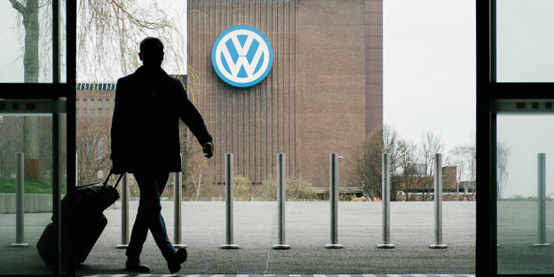 Ein Mann geht durch eine Eingangstür, in der Ferne steht ein VW-Werk. Ein Mann geht durch eine Eingangstür, in der Ferne steht ein VW-Werk.