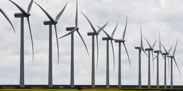 Eine Reihe Windräder stehen nebeneinander auf einem Feld. Eine Reihe Windräder stehen nebeneinander auf einem Feld.