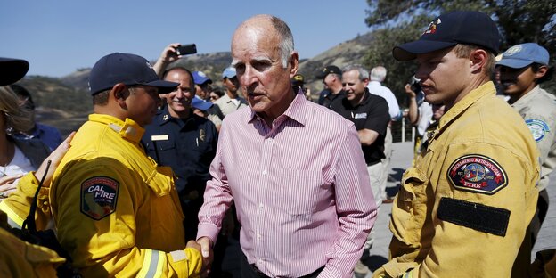 Jerry Brown schüttelt einen Feuerwehrmann die Hand Jerry Brown schüttelt einen Feuerwehrmann die Hand