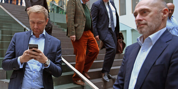 Christian Lindner und René Rock stehen an einer Treppe. Lindner guckt ins Handy Christian Lindner und René Rock stehen an einer Treppe. Lindner guckt ins Handy