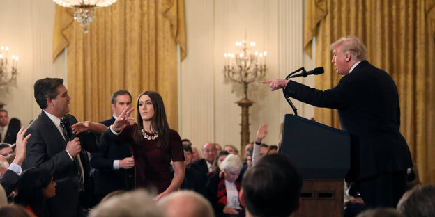 Menschen in einem Saal. Donald Trump zeigt auf einen Mann, der neben einer Frau steht Menschen in einem Saal. Donald Trump zeigt auf einen Mann, der neben einer Frau steht