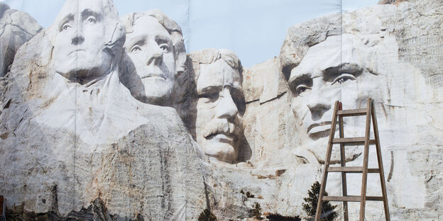Plakatwand mit Mount-Rushmoremotiv und eine Leiter Plakatwand mit Mount-Rushmoremotiv und eine Leiter