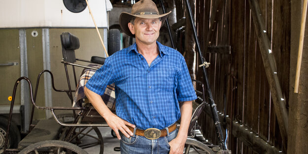 Ein Mann mit Cowboyhut steht in einer Scheune Ein Mann mit Cowboyhut steht in einer Scheune