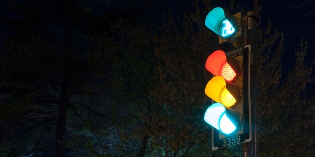 Eine Ampel in der Nacht, bei der alle Lichter leuchten Eine Ampel in der Nacht, bei der alle Lichter leuchten