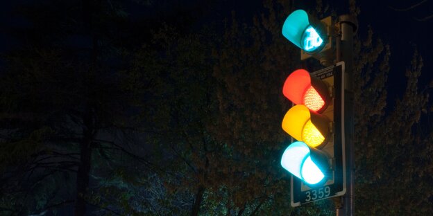 Eine Ampel in der Nacht, bei der alle Lichter leuchten