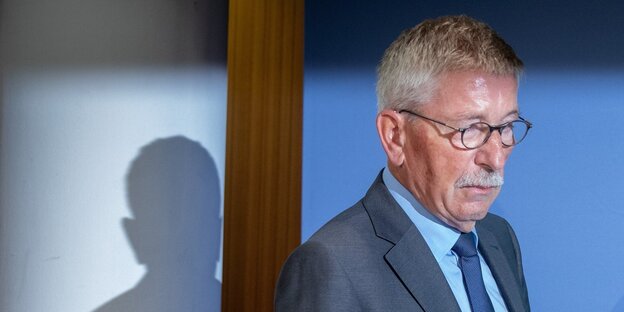 Thilo Sarrazin trägt einen Anzug und läuft nach rechts, im Hintergrund ist sein Schatten zu sehen Thilo Sarrazin trägt einen Anzug und läuft nach rechts, im Hintergrund ist sein Schatten zu sehen