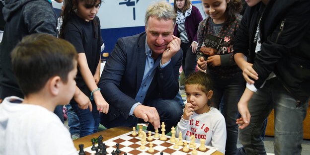 Ein Mann spielt mit Kindern Schach Ein Mann spielt mit Kindern Schach