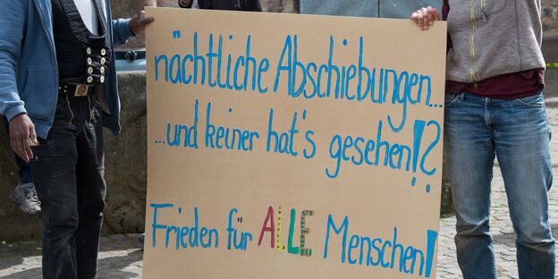 Menschen halten ein schild, mit dem sie gegen Abschiebungen protestieren Menschen halten ein schild, mit dem sie gegen Abschiebungen protestieren