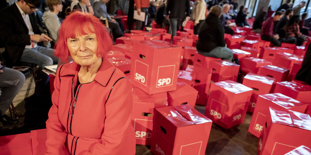 Eine Frau mit roten Haaren und roter Kleidung vor roten SPD-Sitzwürfeln Eine Frau mit roten Haaren und roter Kleidung vor roten SPD-Sitzwürfeln