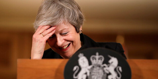 Theresa May lacht und stützt ihren Kopf in die Hand Theresa May lacht und stützt ihren Kopf in die Hand