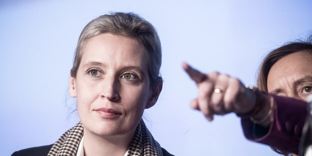 der Kopf einer Frau, daneben eine Frau, die mit ausgestrecktem Arm und Zeigefinger noch vorne zeigt der Kopf einer Frau, daneben eine Frau, die mit ausgestrecktem Arm und Zeigefinger noch vorne zeigt