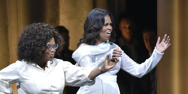 Oprah Winfrey und Michelle Obama halten sich an der Hand und ziehen Grimassen Oprah Winfrey und Michelle Obama halten sich an der Hand und ziehen Grimassen