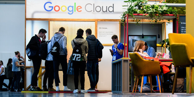 Junge Menschen stehen auf einer Messe an einem Google-Stand Junge Menschen stehen auf einer Messe an einem Google-Stand