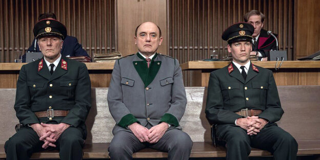 Drei Männer in Uniform sitzen auf einer Bank Drei Männer in Uniform sitzen auf einer Bank
