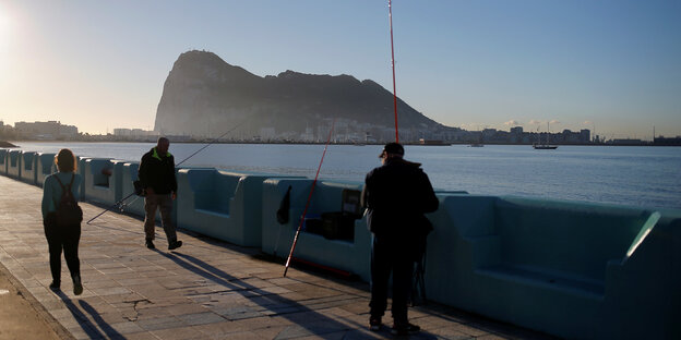 Passanten und Angler an einer Uferpromenade, im Hintergrund Gibraltar Passanten und Angler an einer Uferpromenade, im Hintergrund Gibraltar
