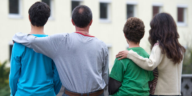 Eine Familie sitzt vor einem Haus Eine Familie sitzt vor einem Haus