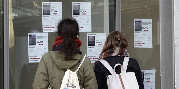 Zwei Personen schauen auf ein Schaufenster, auf dem "Fahndungsaufrufe" mutmaßlicher Rechtsextremisten zu sehen sind