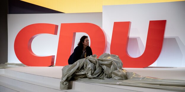 Drei große rote Buchstaben CDU und eine Frau vor einer Abdeckfolie Drei große rote Buchstaben CDU und eine Frau vor einer Abdeckfolie