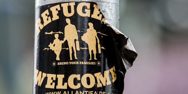 Ein Aufkleber mit der Aufschrift Refugees welcome an einer Stange Ein Aufkleber mit der Aufschrift Refugees welcome an einer Stange