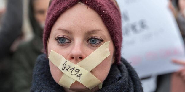 Frau mit zugeklebtem Mund auf Demo