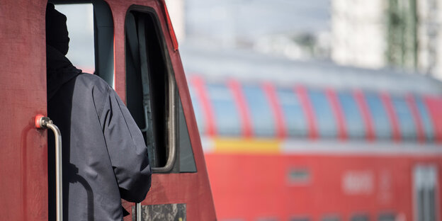 Ein Lokführer steht im Bahnhof an der Tür zu einem Führerstand Ein Lokführer steht im Bahnhof an der Tür zu einem Führerstand