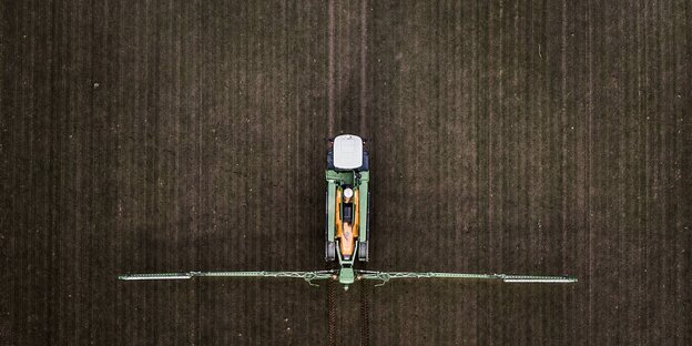 Ansicht von oben auf einen Traktor, der auf einem Feld Pestizide versprüht Ansicht von oben auf einen Traktor, der auf einem Feld Pestizide versprüht