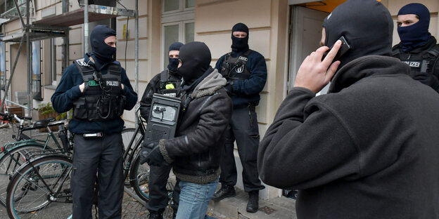Ein Polizist verlässt mit einem Computer im Arm eine Moschee Ein Polizist verlässt mit einem Computer im Arm eine Moschee