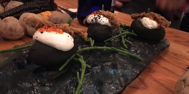 Ein sehr fancy angerichtetes Essen auf einer schwarzen Steinplatte, mit Algen garnier Ein sehr fancy angerichtetes Essen auf einer schwarzen Steinplatte, mit Algen garnier