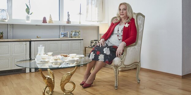 Eine Fraul, Trixie Dörfel, sitzt auf einem Sessel vor einem Couchtisch Eine Fraul, Trixie Dörfel, sitzt auf einem Sessel vor einem Couchtisch