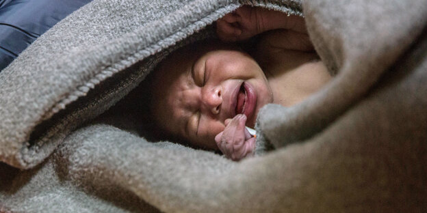 Ein schreiendes Baby liegt eingewickelt in eine Wolldecke Ein schreiendes Baby liegt eingewickelt in eine Wolldecke