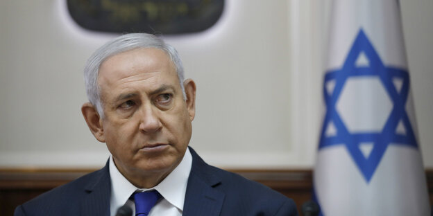 Benjamin Netanjahu, neben ihm eine israelische Flagge Benjamin Netanjahu, neben ihm eine israelische Flagge