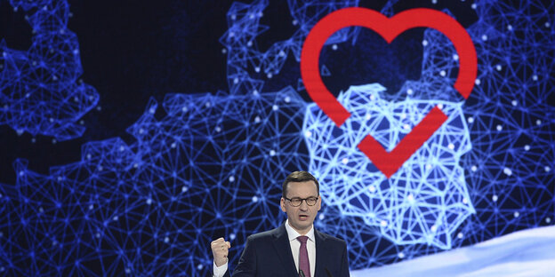 Polens Premierminister Mateusz Morawiecki vor einer Karte, auf der ein Herz über Polen gemalt ist Polens Premierminister Mateusz Morawiecki vor einer Karte, auf der ein Herz über Polen gemalt ist