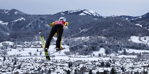 Mann auf Skiern fliegt ins Tal. Im Hintergrund: Berge Mann auf Skiern fliegt ins Tal. Im Hintergrund: Berge