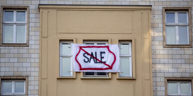 Aus einem Haus hängt ein Transparent mit durchgestrichenem "Sale"-Aufdruck Aus einem Haus hängt ein Transparent mit durchgestrichenem "Sale"-Aufdruck