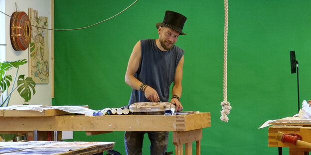 Ein Mann mit Hut steht an einer Holzarbeitsbank Ein Mann mit Hut steht an einer Holzarbeitsbank
