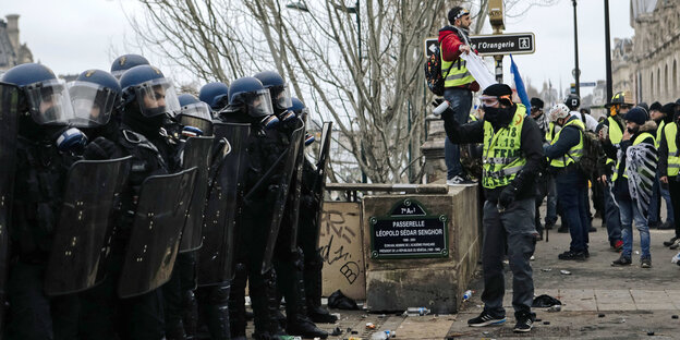 Polizisten stehen während eines Protests Demonstrierenden mit gelben Westen gegenüber Polizisten stehen während eines Protests Demonstrierenden mit gelben Westen gegenüber