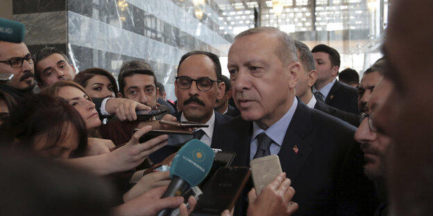 Erdogan steht inmitten von Journalisten und spricht in Mikrofone Erdogan steht inmitten von Journalisten und spricht in Mikrofone