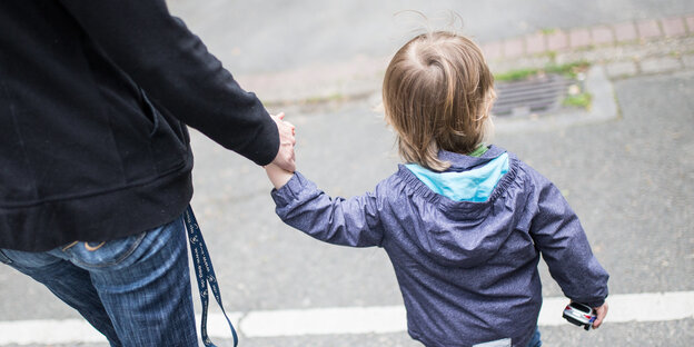 Eine Mutter hält ihren Sohn an der Hand