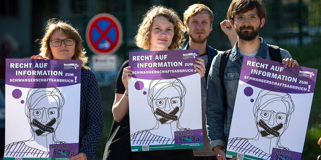 zwei junge Frauen und ein junger Mann demonstrieren mit Schildern gegen den Paragraphen 219a, der Information über abtreibende Ärzte unter Strafe stellt zwei junge Frauen und ein junger Mann demonstrieren mit Schildern gegen den Paragraphen 219a, der Information über abtreibende Ärzte unter Strafe stellt
