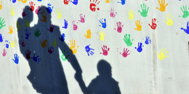 Schatten und farbige Handabdrücke an einer Wand Schatten und farbige Handabdrücke an einer Wand