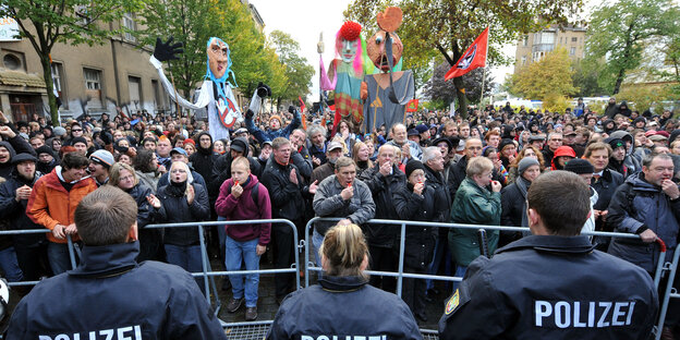 In Leipzig steht eine Menschenmenge hinter einem Absperrgitter vor dem Polizisten stehen In Leipzig steht eine Menschenmenge hinter einem Absperrgitter vor dem Polizisten stehen