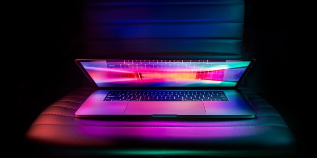 Ein halb zugeklappter Laptop mit leuchtendem Bildschirm Ein halb zugeklappter Laptop mit leuchtendem Bildschirm