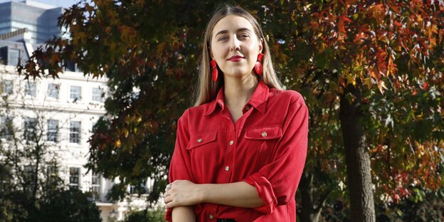 Eine junge Frau in roter Bluse steht in einem Park Eine junge Frau in roter Bluse steht in einem Park