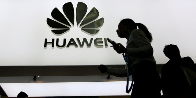 Silhouetten vor einem Huawei-Schild Silhouetten vor einem Huawei-Schild