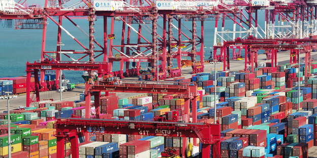 An einem Hafen stehen bunte Container und Containerbrücken An einem Hafen stehen bunte Container und Containerbrücken