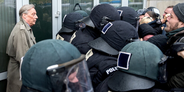Ein Mann wird abgeschirmt von Polizisten Ein Mann wird abgeschirmt von Polizisten